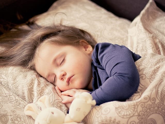A baby sleeping peacefully in a bed
